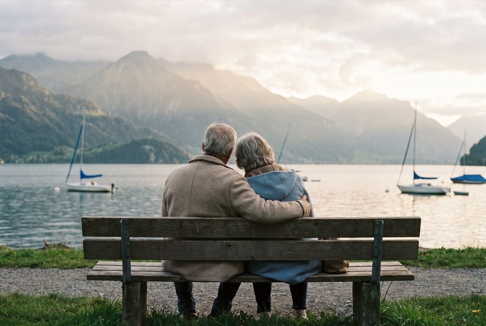 Couple d'âge mûr assis sur un banc au bord d'un lac suisse, vus de dos